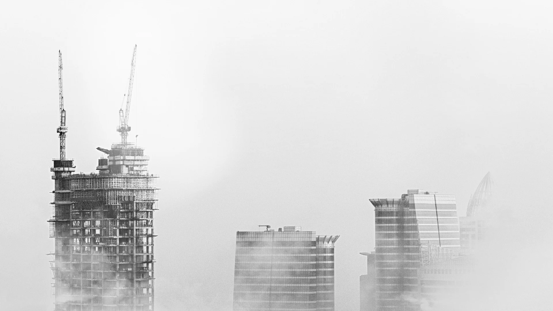 Towers under construction rising through morning mist